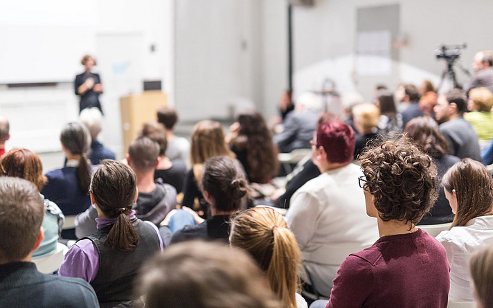 Woman giving presentation in lecture hall at university.