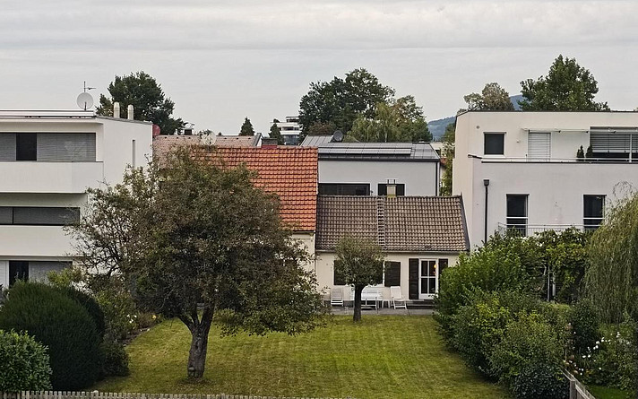 Neubau und Altbau-Gebäude hinter einer Wiese